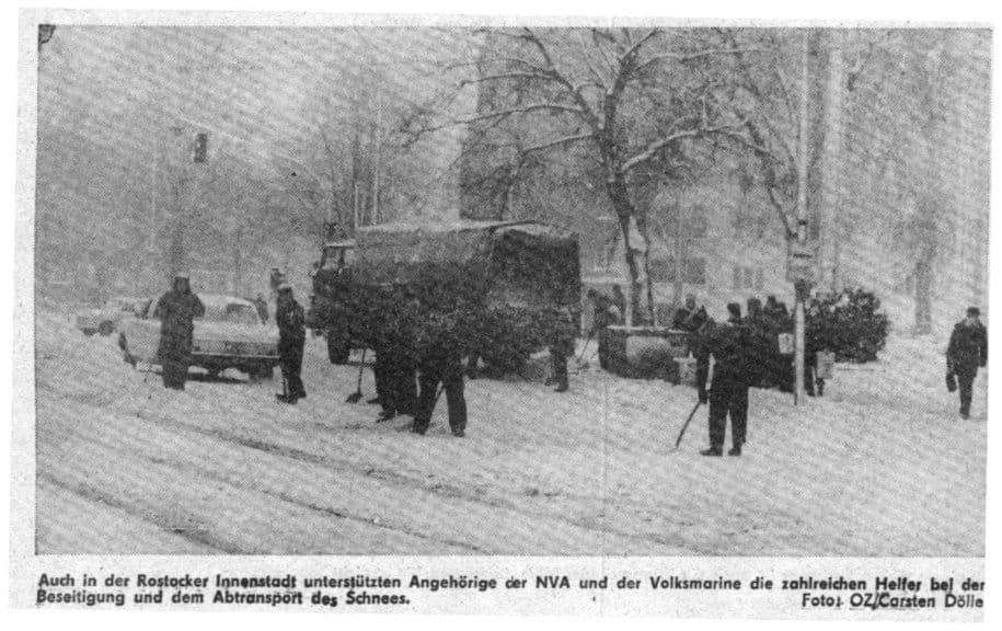 Zeitungsausschnitt mit Foto: Angehörige von NVA und Volksmarine räumen mit einem LKW und Schaufeln Schnee in einer verschneiten Rostocker Straße